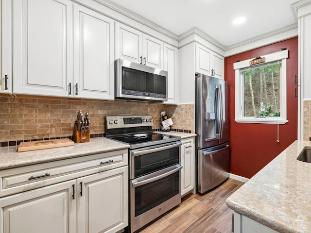 kitchen with stainless steel appliances, light wood-style flooring, white cabinetry, decorative backsplash, and crown molding