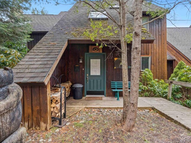 doorway to property featuring roof with shingles