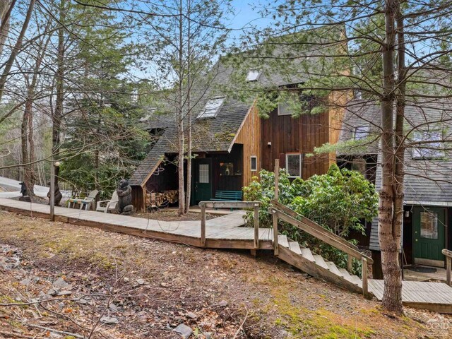 view of front of home with roof with shingles and a wooden deck