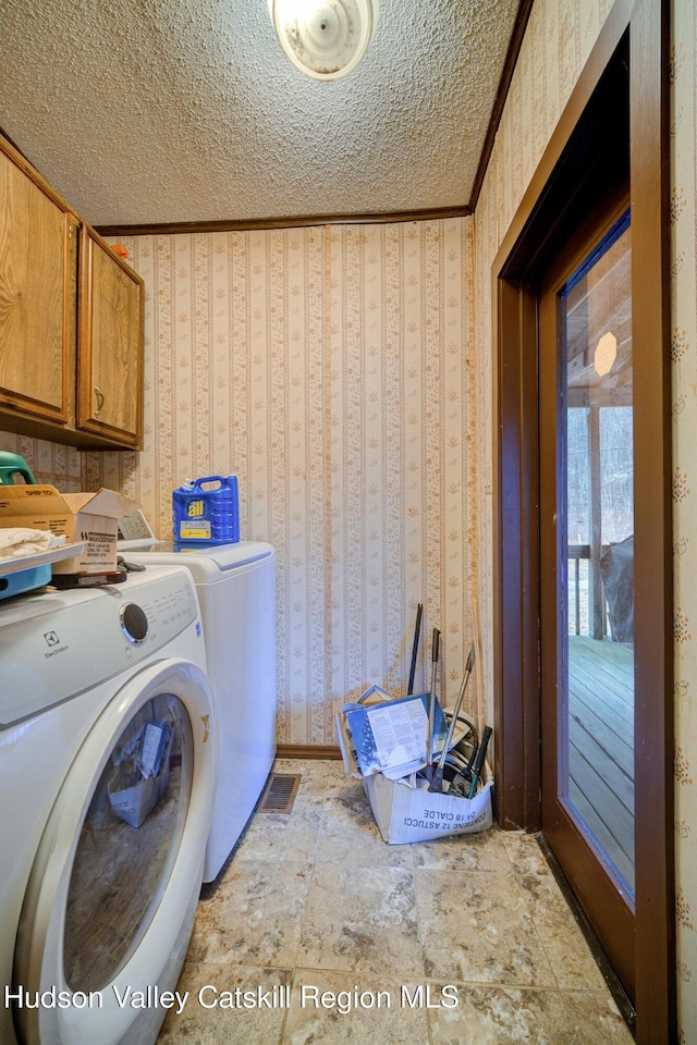 washroom with wallpapered walls, crown molding, washing machine and dryer, cabinet space, and a textured ceiling