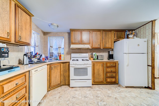 kitchen featuring under cabinet range hood, white appliances, brown cabinetry, and a sink