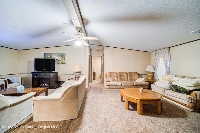 living room with a glass covered fireplace, a textured ceiling, vaulted ceiling with beams, and ceiling fan