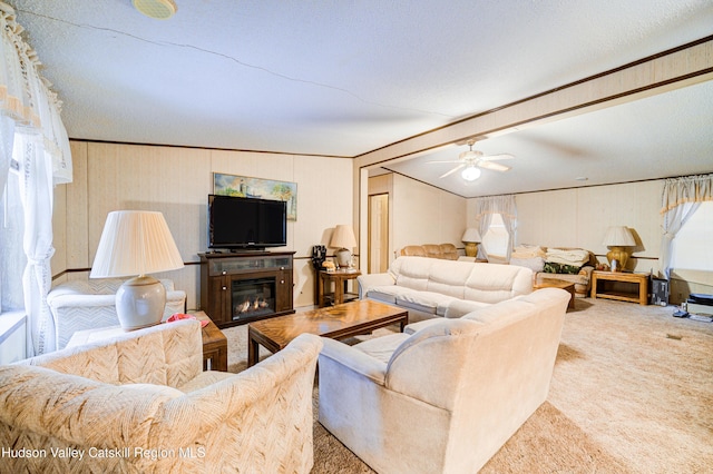 carpeted living area featuring a glass covered fireplace, vaulted ceiling with beams, ceiling fan, and a textured ceiling