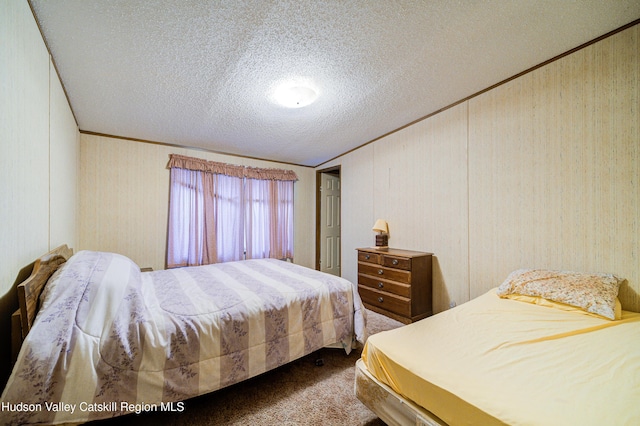 bedroom featuring a textured ceiling, crown molding, and dark colored carpet