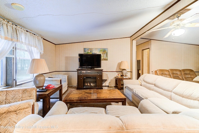 living room featuring lofted ceiling, a glass covered fireplace, and ornamental molding