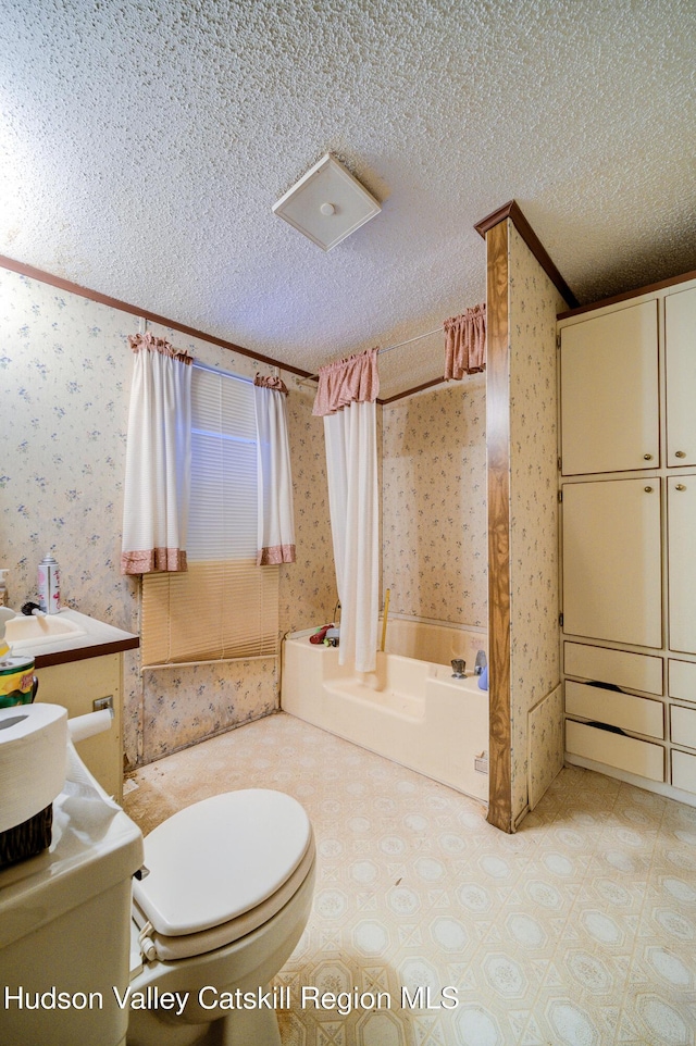 bathroom featuring a sink, a textured ceiling, toilet, and wallpapered walls