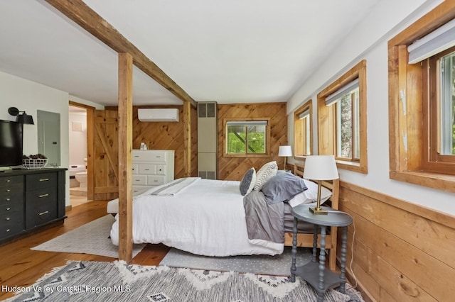 194 High Falls Rd, Saugerties, NY 12477 - bedroom with wooden walls, multiple windows, a wall unit AC, wood finished floors, and connected bathroom