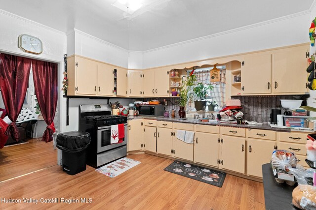 kitchen featuring appliances with stainless steel finishes, light wood-type flooring, crown molding, sink, and cream cabinets