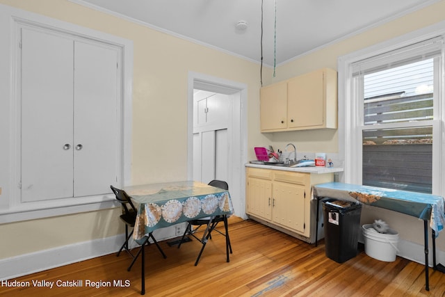 kitchen featuring sink, cream cabinets, ornamental molding, and light wood-type flooring