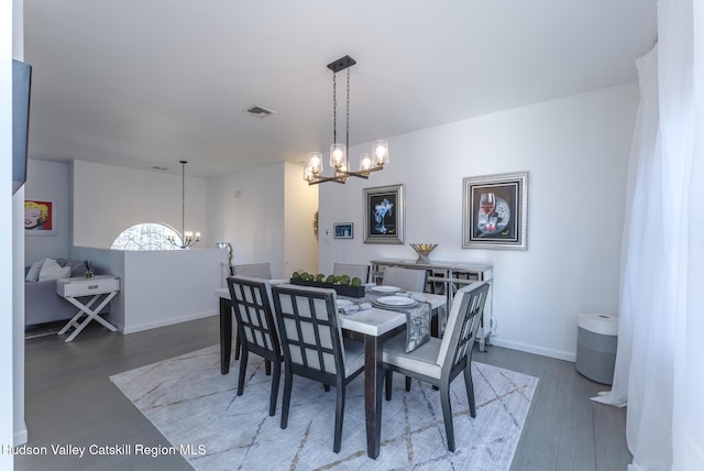 dining area with hardwood / wood-style flooring and an inviting chandelier