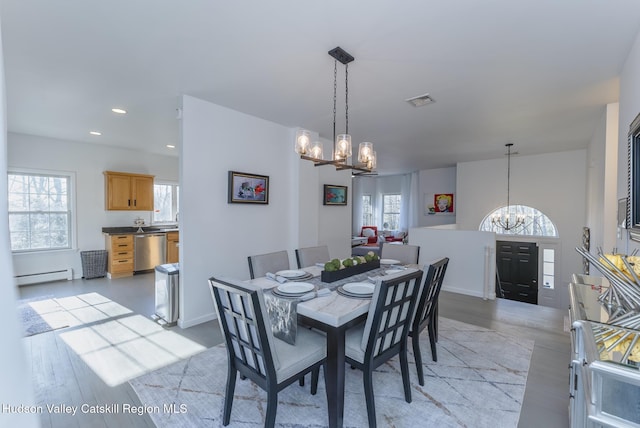 dining room featuring light hardwood / wood-style floors, plenty of natural light, a baseboard radiator, and a notable chandelier