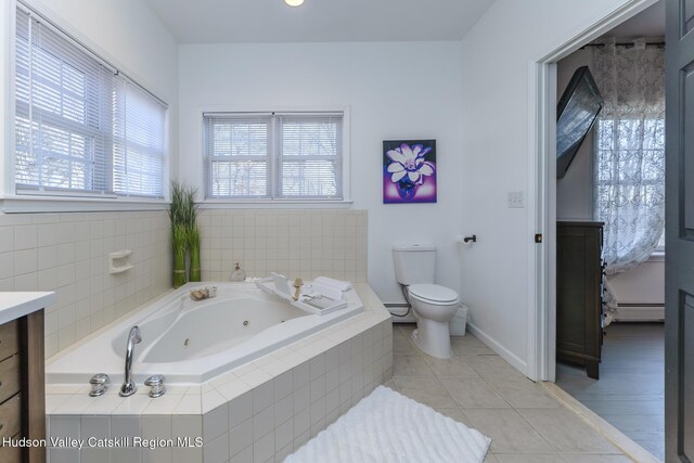 bathroom featuring tile patterned floors, a relaxing tiled tub, a baseboard radiator, and toilet