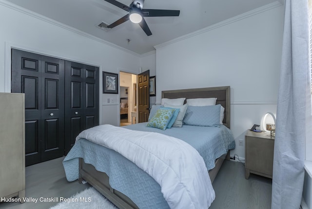 bedroom with hardwood / wood-style floors, a closet, ceiling fan, and ornamental molding