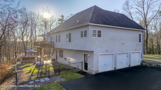 property exterior at dusk featuring a wooden deck and a garage