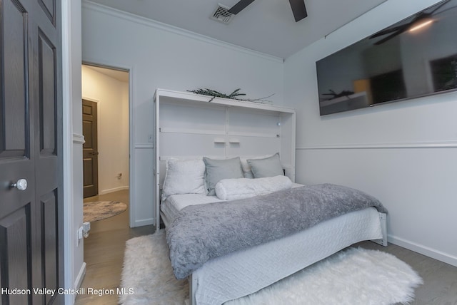 bedroom featuring ceiling fan, wood-type flooring, and ornamental molding