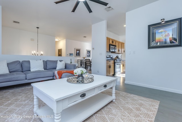 living room featuring ceiling fan with notable chandelier and wood-type flooring