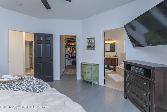 bedroom with ensuite bathroom, ceiling fan, a spacious closet, light hardwood / wood-style floors, and a closet