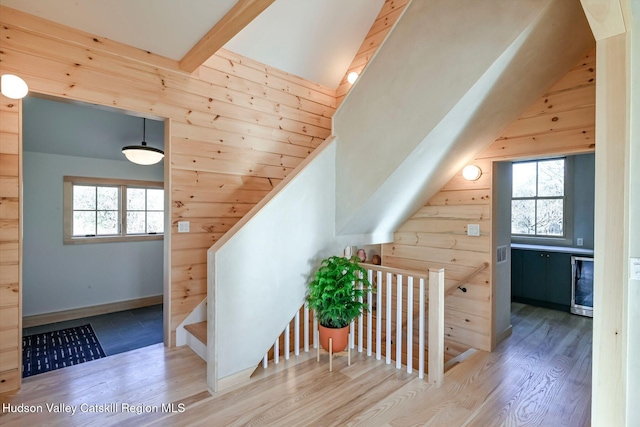 additional living space with vaulted ceiling with beams, wooden walls, and light wood-type flooring