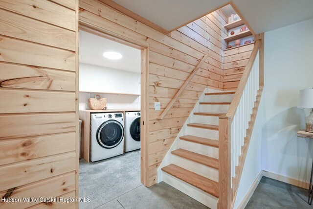 laundry room with washing machine and dryer and wood walls