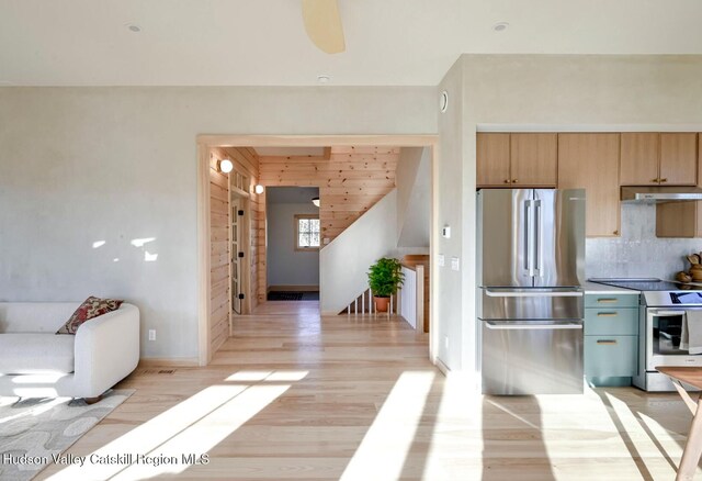 kitchen with backsplash, light hardwood / wood-style flooring, ceiling fan, and appliances with stainless steel finishes