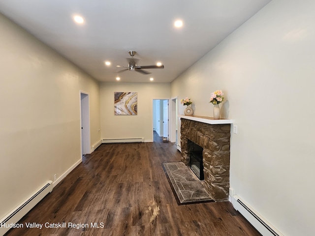 living room featuring dark hardwood / wood-style flooring, a baseboard radiator, and a stone fireplace