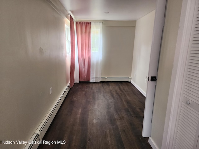 unfurnished room featuring dark wood-type flooring and a baseboard radiator