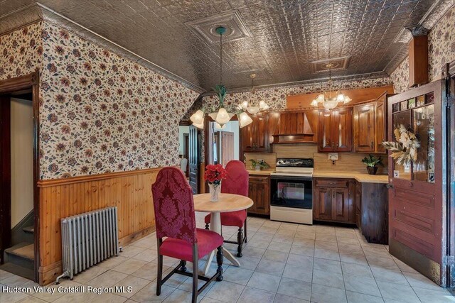 4930 State Route 81, Greenville, NY 12083 - kitchen with electric stove, radiator heating unit, wallpapered walls, wainscoting, and a chandelier