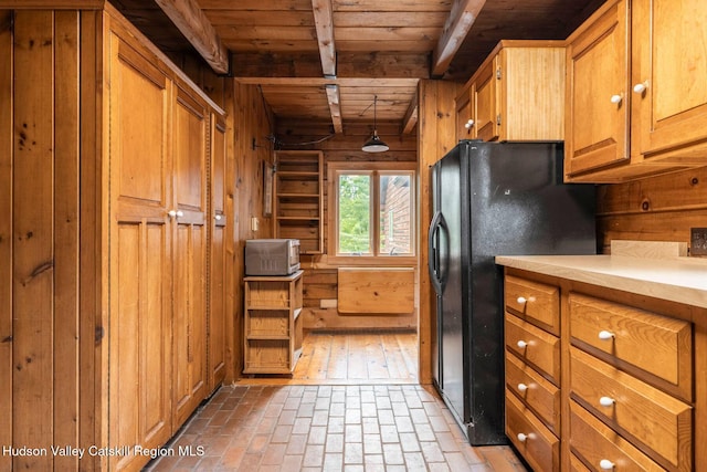 340 Lower Cady Rd, Old Chatham, NY 12136 - kitchen with a wooden ceiling with exposed beams, black refrigerator with ice dispenser, wooden walls, light countertops, and brown cabinetry