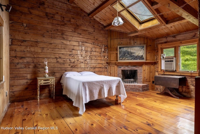 340 Lower Cady Rd, Old Chatham, NY 12136 - bedroom featuring wooden ceiling, wooden walls, hardwood / wood-style floors, a skylight, and a brick fireplace