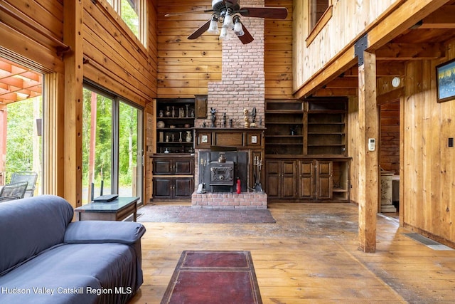 340 Lower Cady Rd, Old Chatham, NY 12136 - living area featuring a wood stove, wood walls, a high ceiling, wood-type flooring, and a ceiling fan