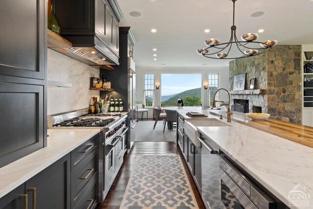 470 Harrington Dr, Austerlitz, NY 12017 - kitchen featuring stainless steel appliances, a sink, a chandelier, light stone countertops, and a stone fireplace
