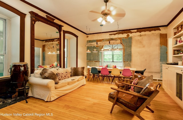 living room featuring ceiling fan, built in features, crown molding, and light wood-type flooring