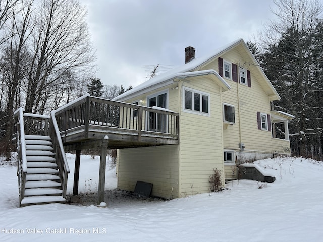 snow covered house featuring a wooden deck