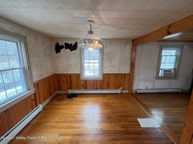 unfurnished dining area with wood-type flooring, baseboard heating, and an inviting chandelier