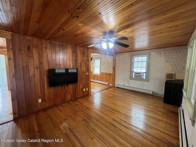 unfurnished living room with hardwood / wood-style flooring, baseboard heating, and wood walls