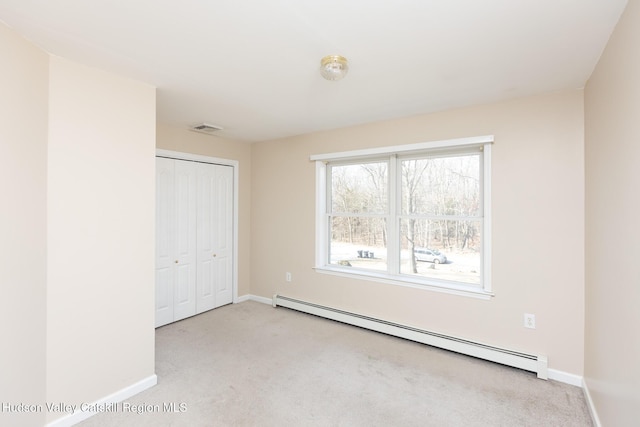 unfurnished bedroom with baseboard heating, carpet flooring, baseboards, and visible vents