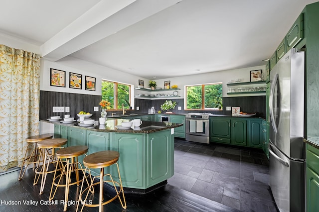 kitchen with plenty of natural light, green cabinets, kitchen peninsula, and stainless steel appliances