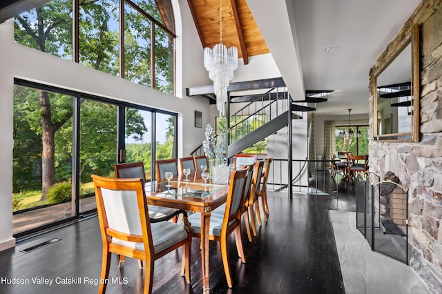 dining area with a healthy amount of sunlight, a fireplace, a chandelier, and dark hardwood / wood-style floors