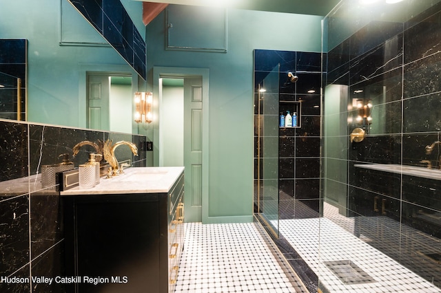 bathroom with tasteful backsplash, vanity, a shower with shower door, and tile walls