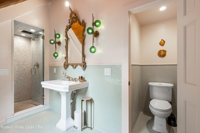 bathroom featuring tile patterned floors, toilet, tile walls, and a shower with shower door