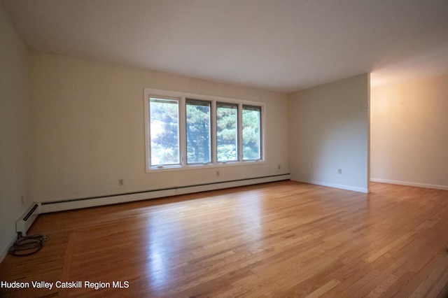 empty room with baseboard heating and light hardwood / wood-style flooring