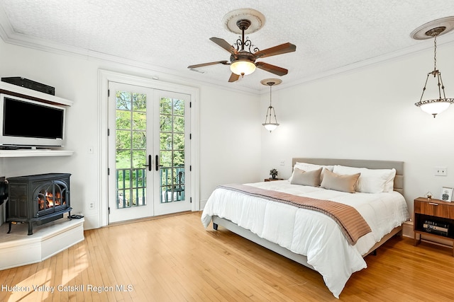 125 Bedell Rd, Poughkeepsie Town, NY 12603 - bedroom featuring access to outside, a textured ceiling, a wood stove, ornamental molding, and light wood-style floors