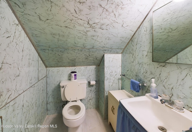 bathroom featuring vanity, vaulted ceiling, tile patterned flooring, and toilet