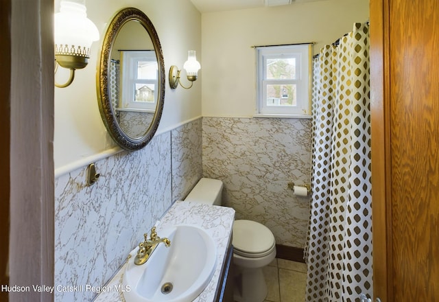 bathroom featuring sink, toilet, tile walls, and tile patterned floors