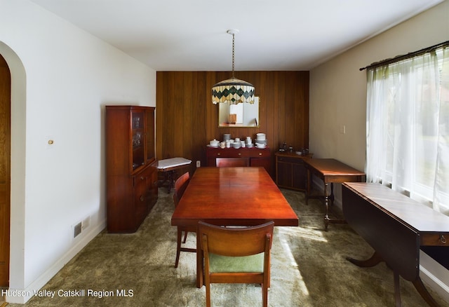 carpeted dining room with wood walls