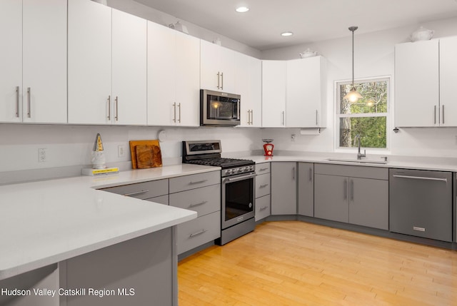 kitchen featuring light countertops, gray cabinets, appliances with stainless steel finishes, and a sink