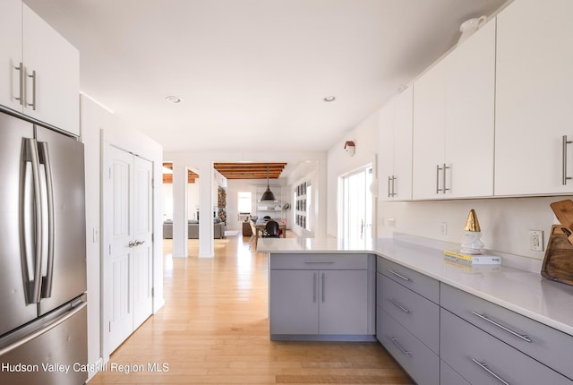 kitchen with light wood-style floors, light countertops, gray cabinets, freestanding refrigerator, and a peninsula