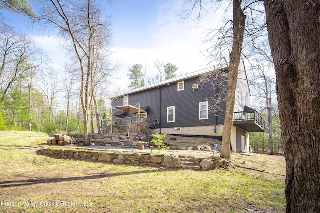rear view of property featuring a garage, a yard, and a deck