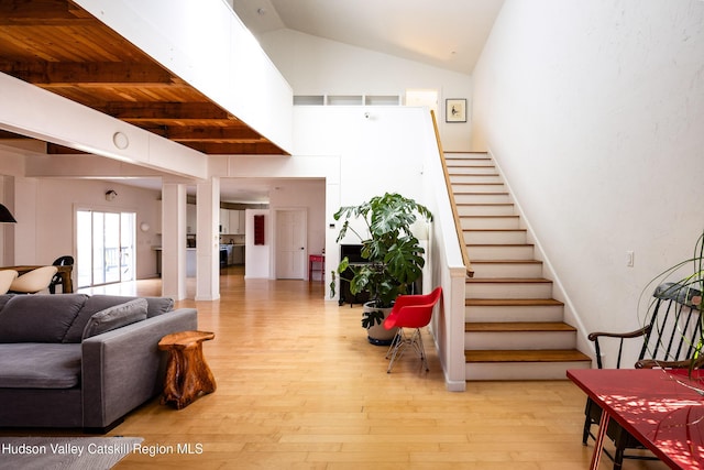 stairs with vaulted ceiling with beams and hardwood / wood-style flooring