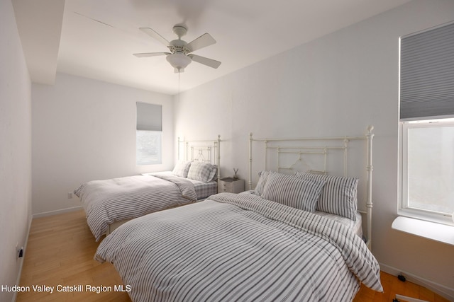 bedroom featuring baseboards, multiple windows, and light wood-style floors